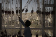 Mohammed Zakir closes the curtains of his family home, overlooking Kabul, Afghanistan, Friday, Sept. 17, 2021. Zakir's bother, Zaki Anwari, was a 17-year-old soccer player who died after trying to board a departing U.S. Air Force C-17 on Aug. 16 at Kabul's airport. (AP Photo/Felipe Dana)