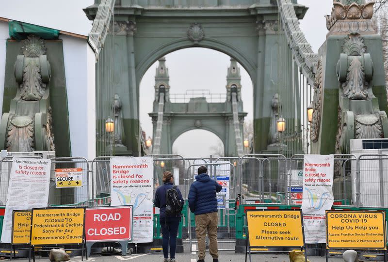 Pedestrians view Hammersmith Bridge, the closure of which has caused the annual Oxford versus Cambridge boat race on the River Thames to be relocated, London, Britain