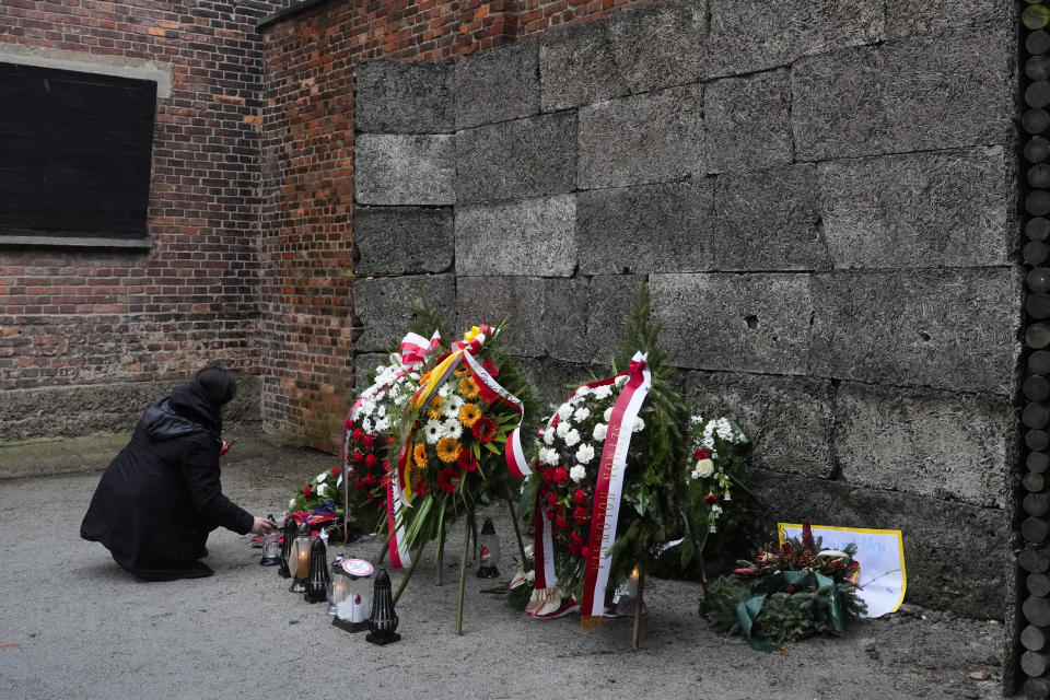 A woman lights candles in front of the Death Wall in the Auschwitz Nazi death camp in Oswiecim, Poland, Saturday, Jan. 27, 2024. Survivors of Nazi death camps marked the 79th anniversary of the liberation of the Auschwitz-Birkenau camp during World War II in a modest ceremony in southern Poland.(AP Photo/Czarek Sokolowski)