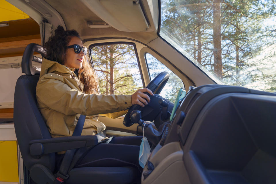 Side view of woman driving a caravan in nature at sunset