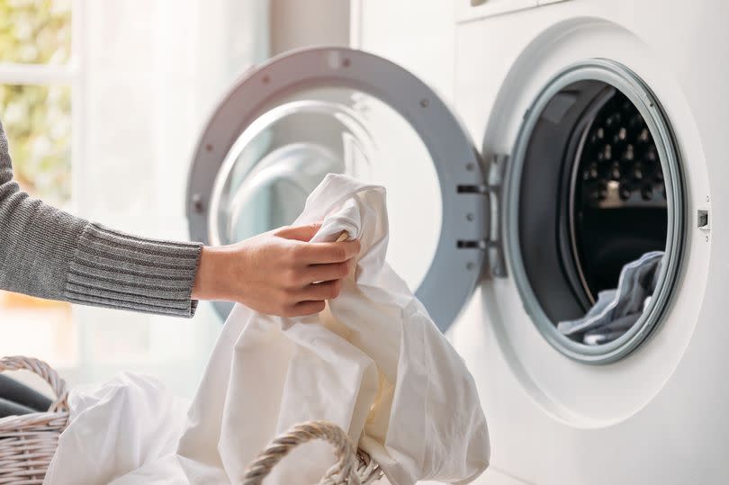 Close up of female hands dropping dirty laundry in the washing machine