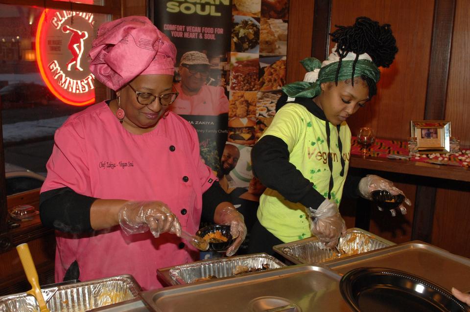 Chef Zakiya Courtney of Vegan Soul, left, serves guests during the Lubar Center's African American Heritage Dinner.