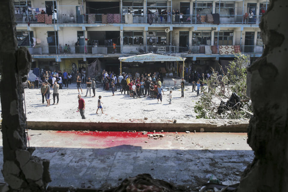 Palestinians look at the aftermath of the Israeli strike on a U.N.-run school that killed dozens of people in the Nusseirat refugee camp in the Gaza Strip, Thursday, June 6, 2024. An Israeli strike early Thursday on a school sheltering displaced Palestinians in central Gaza killed more than 30 people, including 23 women and children, according to local health officials. The Israeli military said that Hamas militants were operating from within the school. (AP Photo/Jehad Alshrafi)