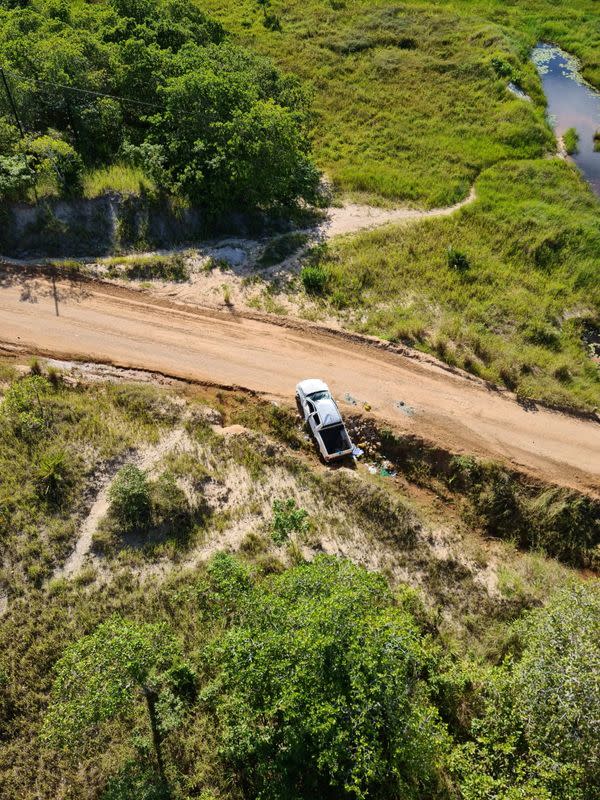 A car involved in an ambush on a convoy of vehicles lies wrecked on the side of the road