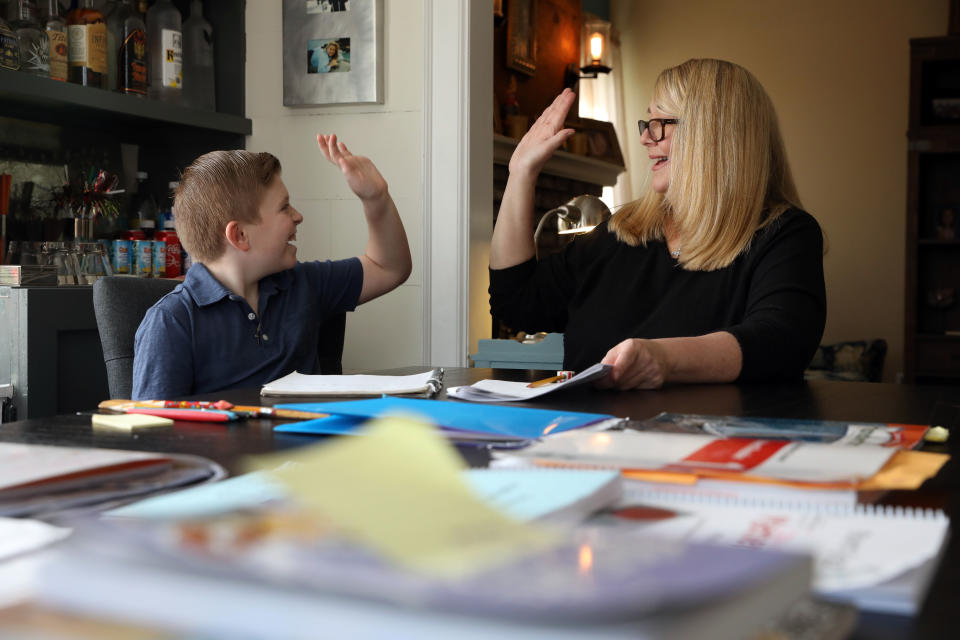 March 18, 2020; Larchmont, NY, USA; Fourth-grader Gavin Tecza hi-fives his mother, Suzanne Tecza, while working on his assignment about pioneer fun at their home in Larchmont March 18, 2020. Tecza, a library specialist at a local school, has set up a schedule to homeschool her son at home during their self-quarantine.. Mandatory Credit: Tania Savayan/The Journal News via USA TODAY NETWORK/Sipa USA