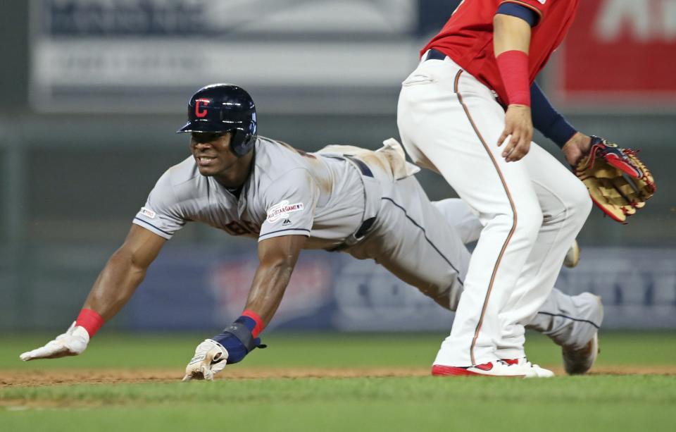 Cleveland Indians' Yasiel Puig, left, dives into third base, advancing from first after an error on a pickoff attempt at first in the ninth inning of a baseball game against the Minnesota Twins Friday, Aug. 9, 2019, in Minneapolis. The Indians won 6-2. (AP Photo/Jim Mone)
