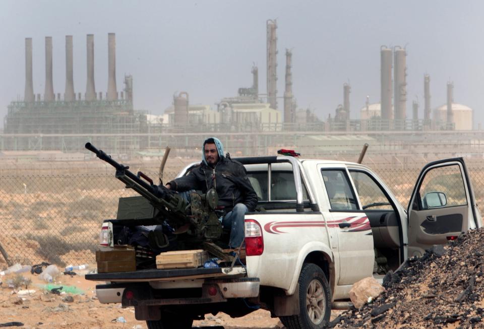 FILE - In this March 5, 2011 file photo, an anti-government rebel sits with an anti-aircraft weapon in front an oil refinery in Ras Lanouf, eastern Libya. Libya has been plunged into chaos again, with forces loyal to a polarizing military commander marching on the capital and trading fire with militias aligned with a weak U.N.-backed government. (AP Photo/Hussein Malla, File)