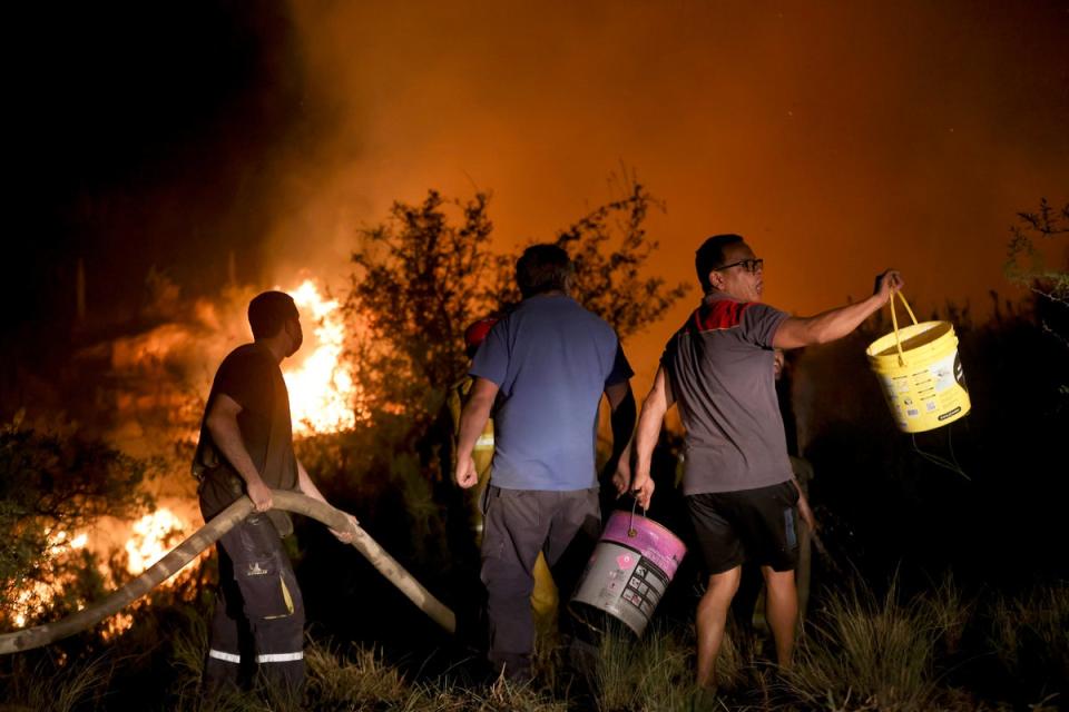 Vecinos trabajan para apagar un incendio forestal en las afueras de Villa Carlos Paz en la provincia de Córdoba (AP)