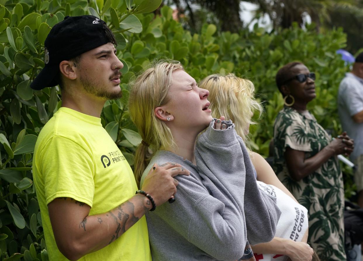 In this June 25 photo, Ariana Hevia, of New Orleans, center, stands with Sean Wilt, left, near the beachfront condo building that collapsed in Surfside, Fla. Hevia's mother, Cassondra Billedeau-Stratton, was among those who died in the collapse. 