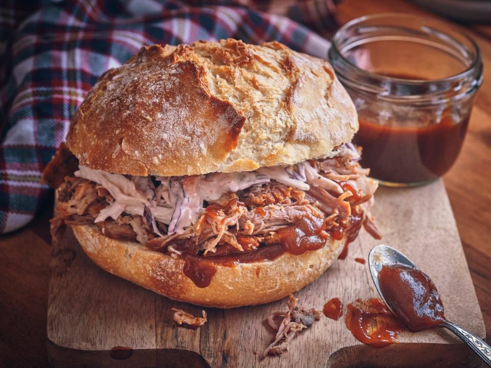 pulled pork sandwich on a wooden board with barbecue sauce