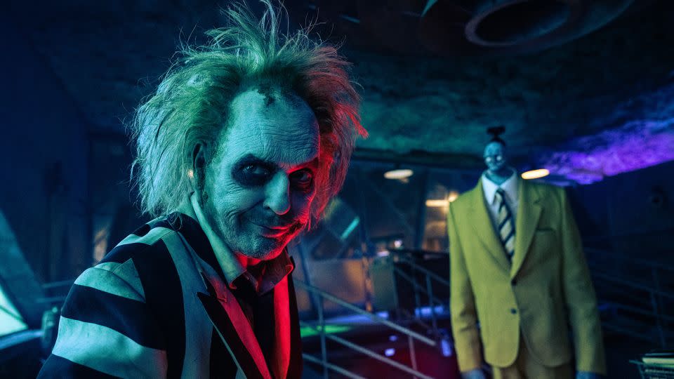 Beetlejuice and Bob the shrinker, whose gold suit was inspired by Century 21 Real Estate employees of the 1980s. - Warner Brothers Discovery