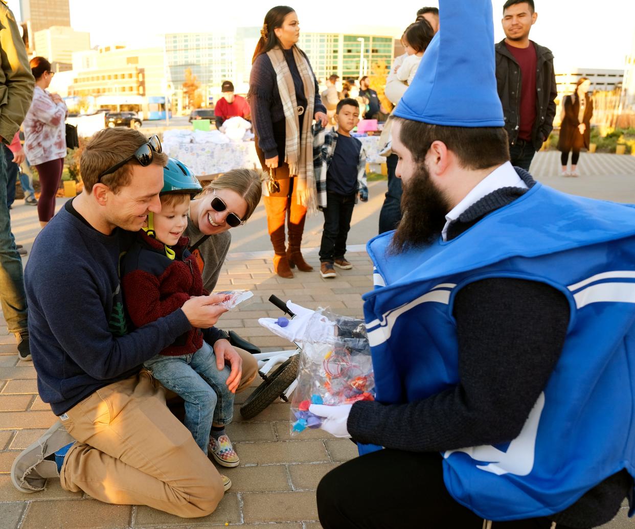 A family visits with Dreidel Man, portrayed by Berel Grossbaum, during a community Chanukah celebration at Scissortail Park's Love's Travel Stops Stage and Great Lawn in downtown Oklahoma City.