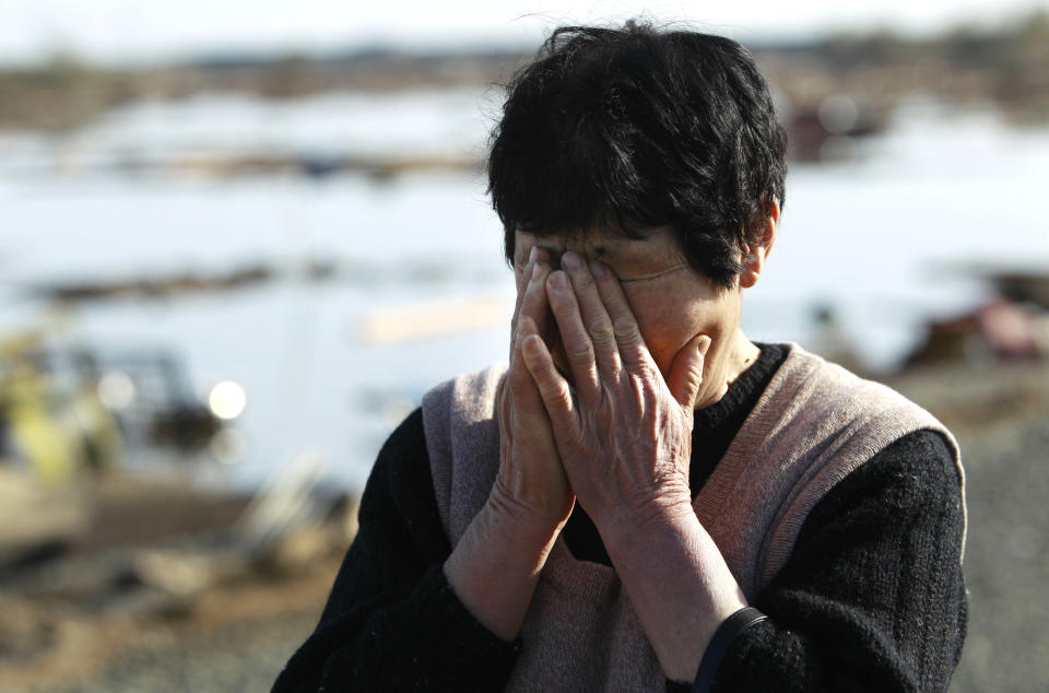 FILE - A resident wipes tears as she finds no remains of her home on March 14, 2011, in Soma, Fukushima Prefecture, Japan, three days after a massive earthquake and tsunami struck the country's north east coast. The 2011 quake, tsunami and nuclear meltdown in northern Japan provides a glimpse of what Turkey and Syria could face in the years ahead. No two events are alike, but the recent disaster resembles Japan's in the sheer enormity of the psychological trauma, of the loss of life and of the material destruction. (AP Photo/Wally Santana, File)