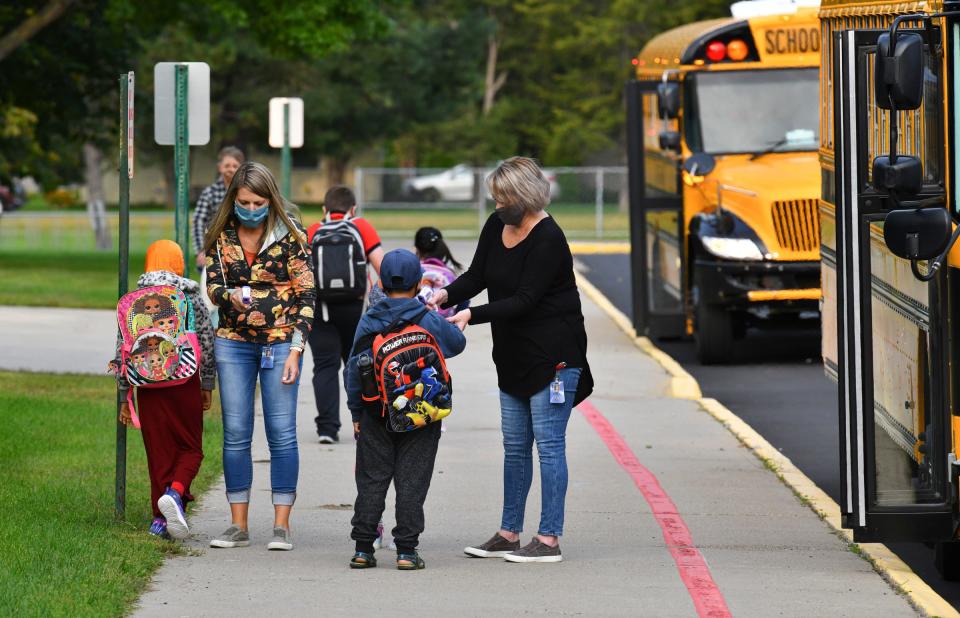 Staff members check temperatures of students as they leave their buses to start the first day of in-person instruction Monday, Sept. 14, 2020, at Westwood Elementary School in St. Cloud.