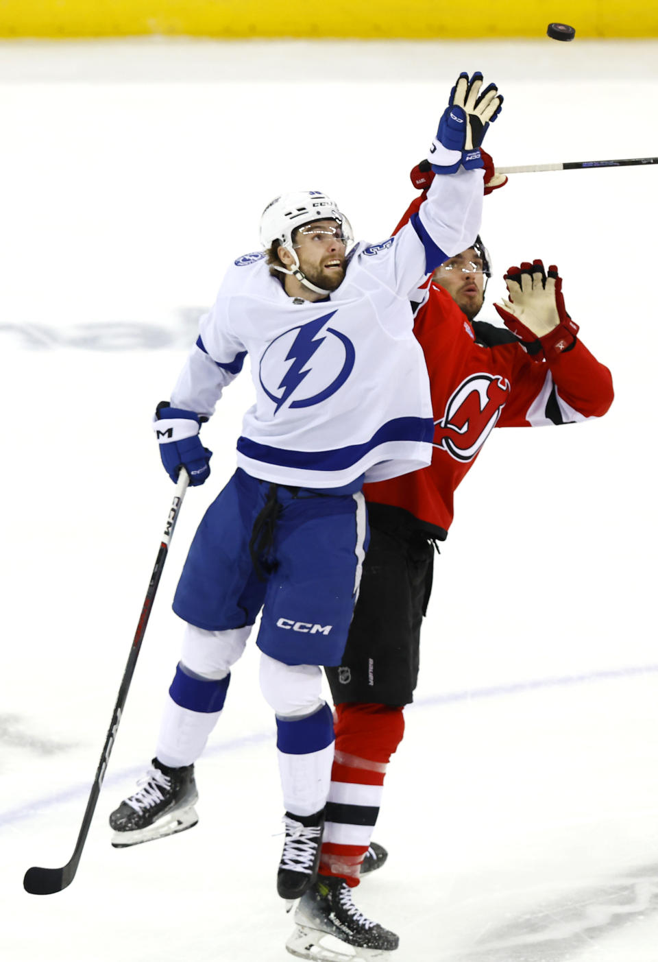 Tampa Bay Lightning left wing Brandon Hagel, left, bats the puck against New Jersey Devils defenseman Kevin Bahl, right, during the third period of an NHL hockey game, Sunday, Feb. 25, 2024, in Newark, N.J. The Tampa Bay Lightning won 4-1.(AP Photo/Noah K. Murray)