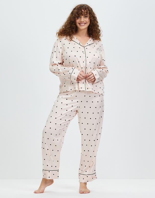 A model stands smiling in off white polka dot sleep wear