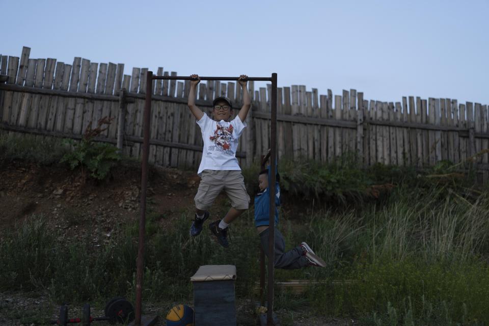 Twelve-year-old Gerelt-Od Kherlen does pull ups with his younger brother Gerelt-Ireedui Kherlen at their home in a Ger district on the outskirts of Ulaanbaatar, Mongolia, Tuesday, July 2, 2024. Growing up in a Ger district without proper running water, Gerelt-Od fetched water from a nearby kiosk every day for his family. Carrying water and playing ball with his siblings and other children made him strong and resilient. (AP Photo/Ng Han Guan)