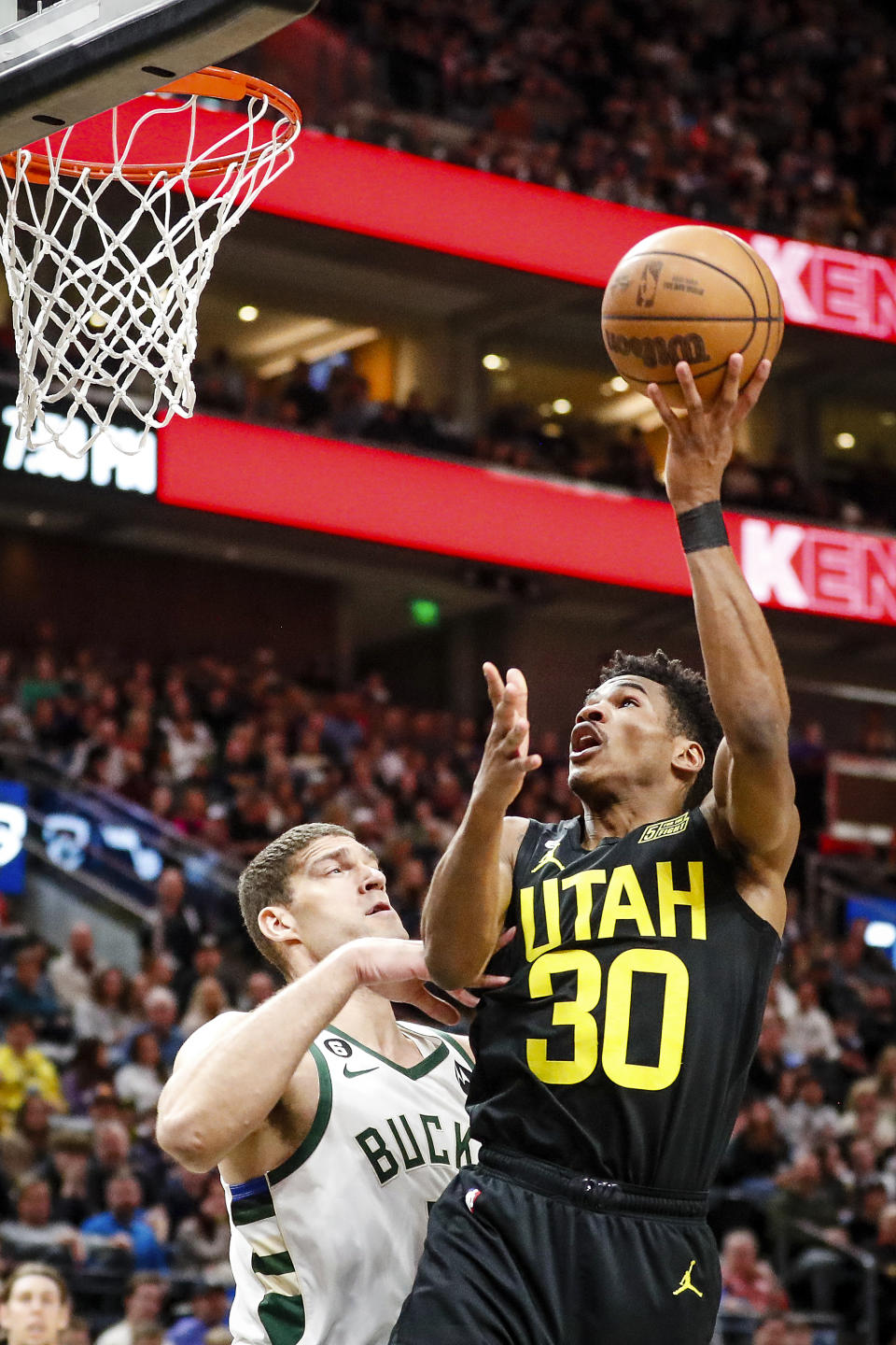 Utah Jazz guard Ochai Agbaji (30) shoots over Milwaukee Bucks center Brook Lopez, left, during the first half of an NBA basketball game Friday, March 24, 2023, in Salt Lake City. (AP Photo/Adam Fondren)