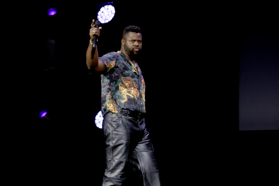 Winston Duke onstage holding up a mic