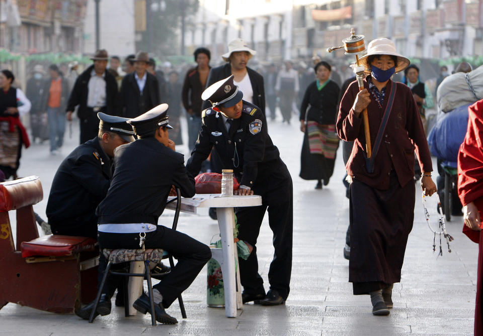 FILE - In this June 19, 2009 file photo, security guards keep watch over Buddhist pilgrims as they walk on the Barkhor, the circular route around the Jokhang Temple in Lhasa, the capital of Tibet, China. Tibet is seeing a boom in Chinese visitors, meaning that the government's latest ban on foreigners following self-immolation protests against Beijing's rule has barely dented the region's tourism industry. (AP Photo/Greg Baker, File)