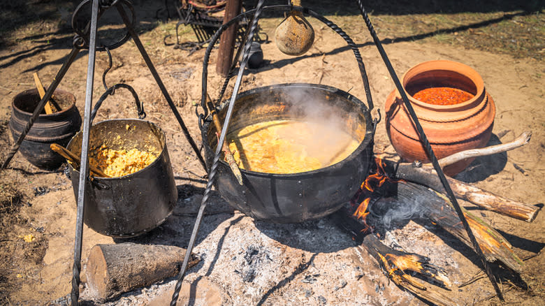 Cauldrons of soup cooking over a fire