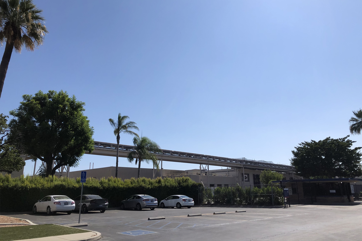 Abandoned Busch Gardens, Van Nuys, California, parking lot with a few cars in the foreground in front of park, a dramatic blue sky in the background