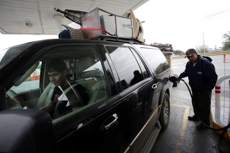 A man part of the "12th Caravan of Migrants" fills his car with gasoline in Matehuala