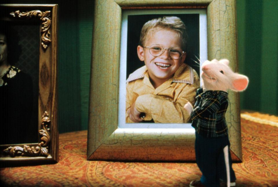 Stuart Little stands next to a framed photograph of a boy named George