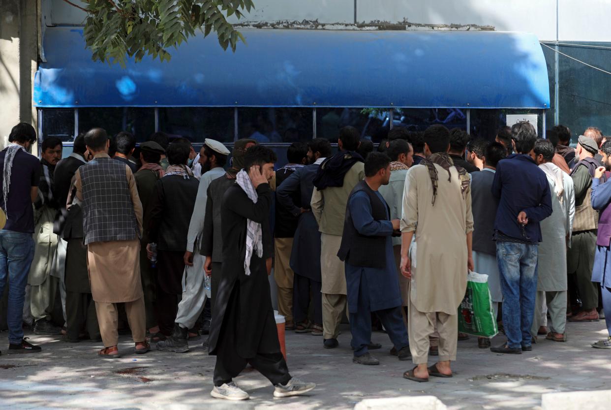 Afghans wait in long lines for hours to try to withdraw money in front of Kabul Bank in Kabul, Afghanistan on Sunday, Aug. 15, 2021. Officials say Taliban fighters have entered Kabul and are seeking the unconditional surrender of the central government.