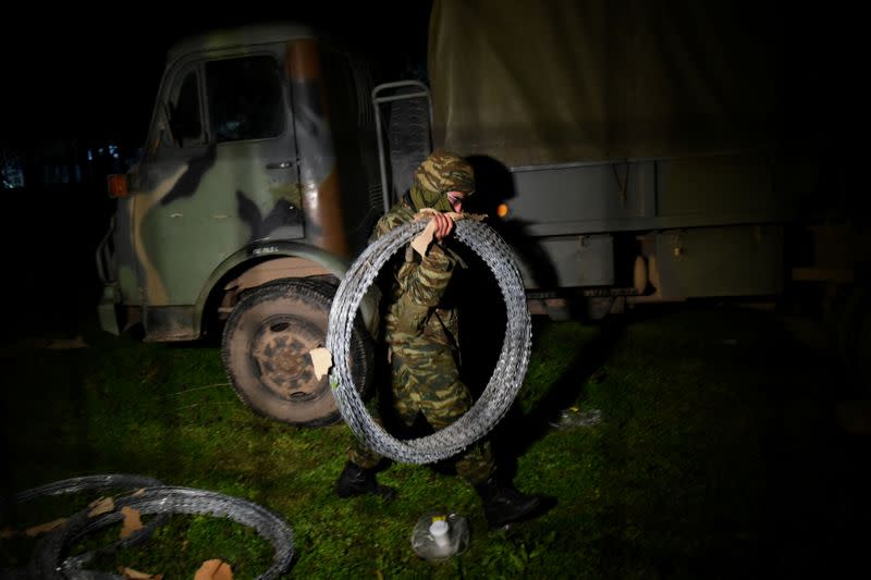 A Greek soldier carries barbed wire to reinforce the border fence at the Kastanies border crossing with Turkey's Pazarkule, as migrants who want to cross into Greece from Turkey gather at the borderline, in the region of Evros