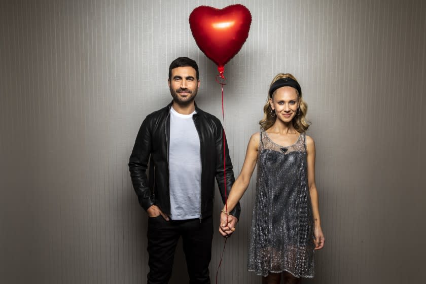 Actors Brett Goldstein, left and Juno Temple holds hands and a red balloon