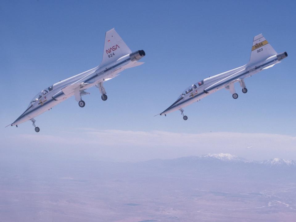 A pair of T-38s dive toward a runway at Edwards Air Force Base in Calif.