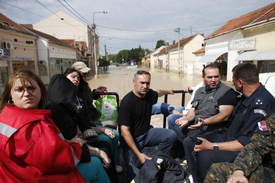 People travel on a truck through a flooded street in Obrenovac