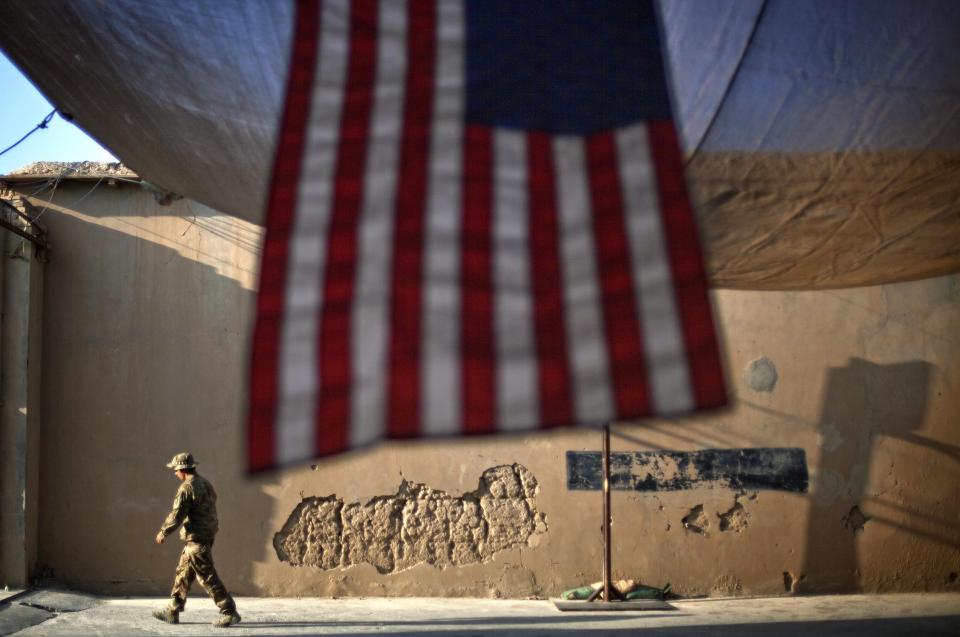 FILE - In this Sept. 11, 2011 file photo, A U.S. Army soldier with the 25th Infantry Division, 3rd Brigade Combat Team, 2nd Battalion 27th Infantry Regiment walks past an American Flag hanging in preparation for a ceremony commemorating the tenth anniversary of the 9/11 attacks, Sept. 11, 2011 at Forward Operating Base Bostick in Kunar province, Afghanistan. Most Afghans want US and NATO troops to leave Afghanistan once a peace deal to end Afghanistan's 18-year war is signed with the Taliban, according to a survey carried out by the American Institute of War and Peace Studies. The survey conducted in 2019, between Nov. 23 and Dec. 20 has a five percent margin of error. (AP Photo/David Goldman, File)