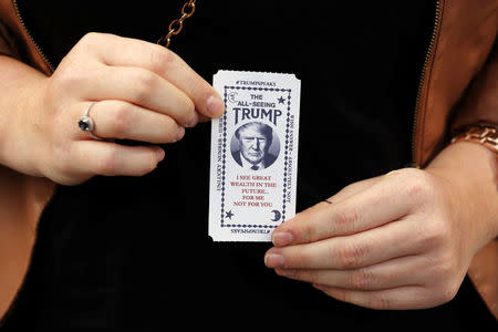 A woman holds a ticket dispensed from a Donald Trump themed fortune telling machine in Columbus Circle in New York, U.S., October 12, 2016. REUTERS/Lucas Jackson