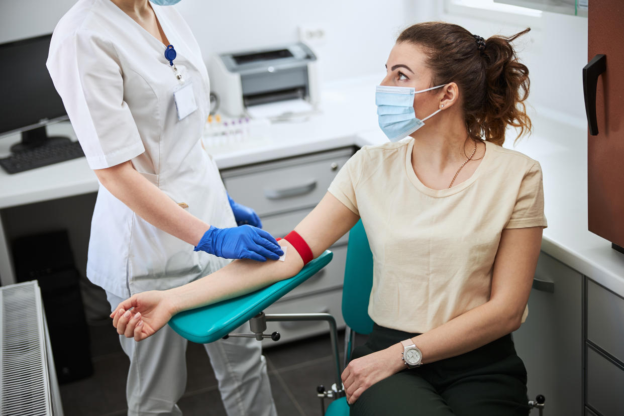 Nurse in sterile gloves cleansing the area on the patient arm with an alcohol pad before blood drawing