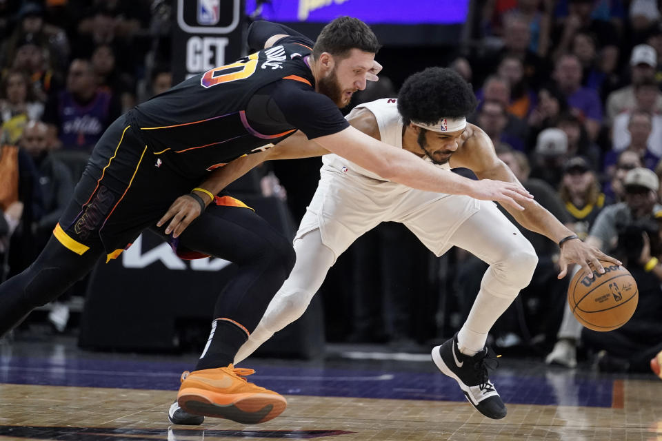 Phoenix Suns center Jusuf Nurkic (20) reaches for the ball, while Cleveland Cavaliers center Jarrett Allen (31) gets a hand on it during the first half of an NBA basketball game in Phoenix, Wednesday, April. 3, 2024. (AP Photo/Darryl Webb)