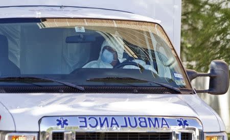 An ambulance driver wearing a protective suit escorts Amber Joy Vincent (not shown), the second health worker to be infected with the Ebola virus at Texas Health Presbyterian Hospital to the airport in Dallas, Texas October 15, 2014. REUTERS/Jaime R. Carrero