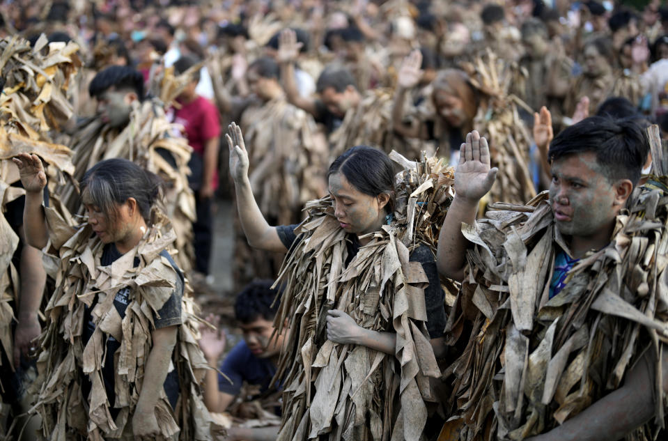 Devout Catholics, dressed in dried banana leaves, pray outside the church of Saint John the Baptist during the mud festival at Bibiclat, Nueva Ecija province, northern Philippines, Monday, June 24, 2024. (AP Photo/Aaron Favila)