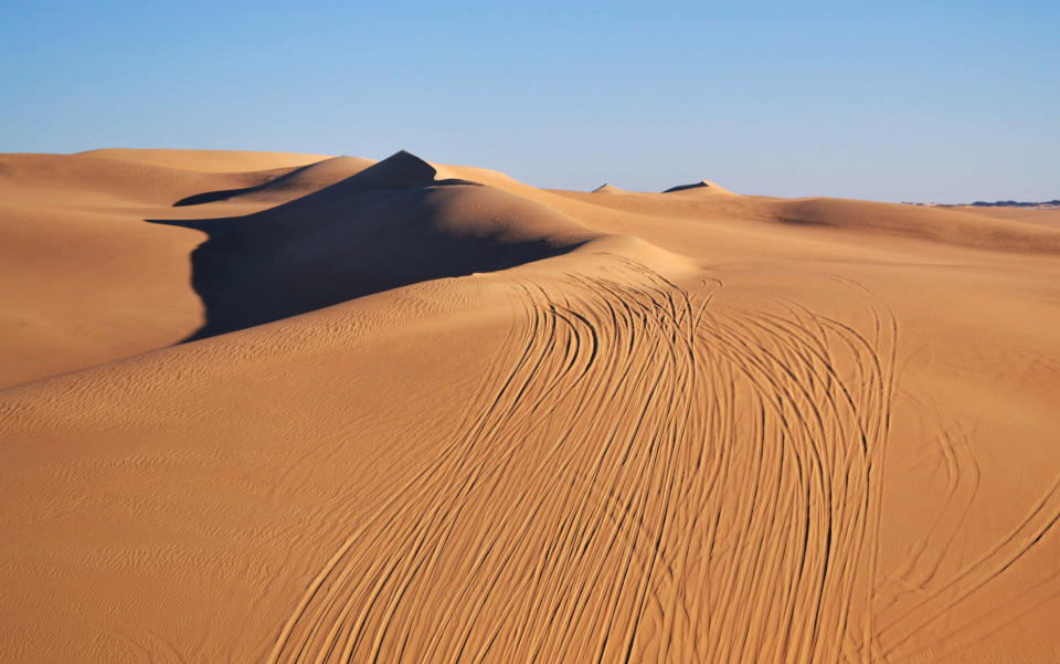 This September 2012 photo shows tracks from four-wheel drives lining the Great Sand Sea, a vast desert with huge rolling sand dunes that span the Egyptian and Libyan frontiers in the Egyptian oasis of Siwa, a Berber town of some 27,000 people roughly 450 miles (about 725 kilometers) southwest of Cairo. The palm tree-lined area is known for its quiet charm, ancient ruins, abundant natural springs, a vast salt lake and rolling sand dunes in the surrounding desert. (AP Photo/Kim Gamel)