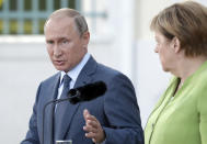 German Chancellor Angela Merkel, right, and the President of Russia, Vladimir Putin, left, address the media during a joint statement prior to a meeting at the government guest house Meseberg in Gransee near Berlin, Germany, Saturday, Aug. 18, 2018. (AP Photo/Michael Sohn)