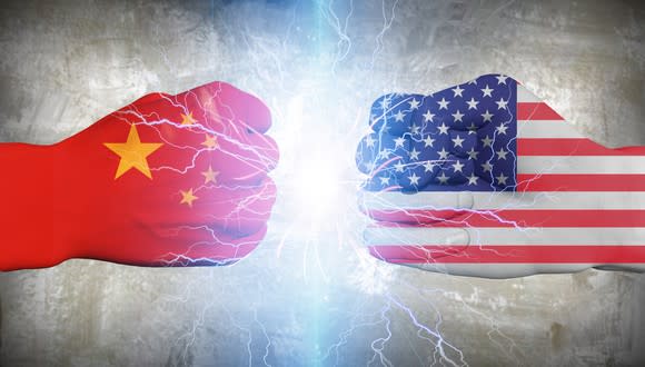 Two fists facing each other, one painted with China flag and one with U.S. flag.