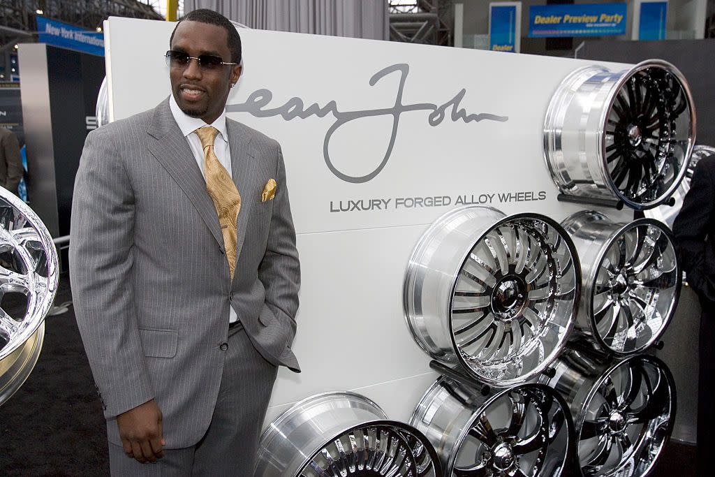 Sean "P. Diddy" Combs poses next to a group of the Sean-John branded aluminum wheels that he is partnering with Weld Wheels, of Kansas City, Missouri, to produce, during the New York International Auto Show