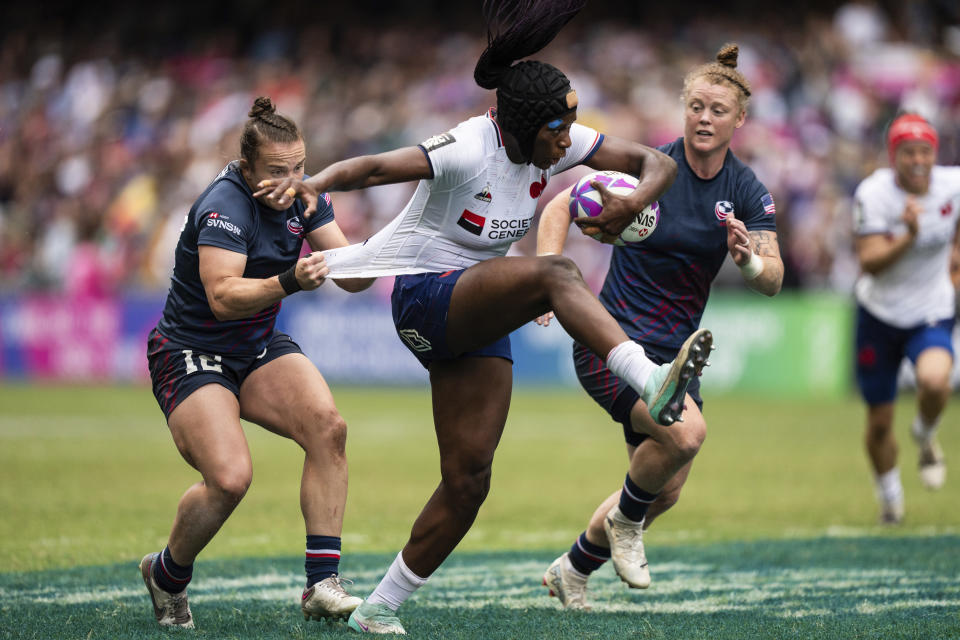 Seraphine Okemba, center, of France is tackled by Kristi Kirshe of the United States during the women semifinal match in the Hong Kong Sevens rugby tournament in Hong Kong, Sunday, April 7, 2024. (AP Photo/Louise Delmotte)