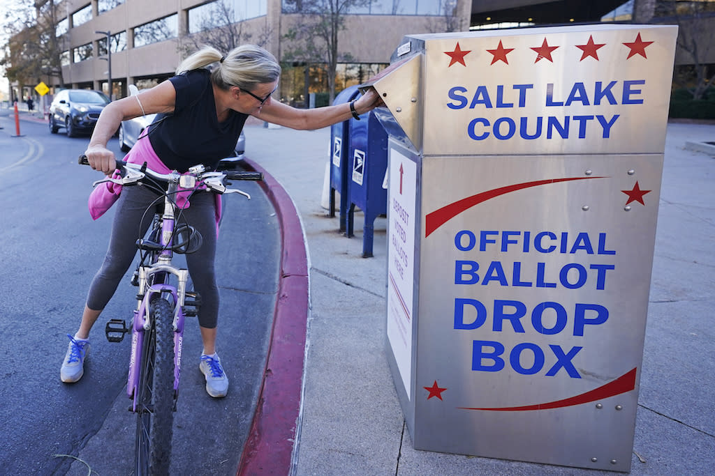 A woman putting a ballot in a drop-off box