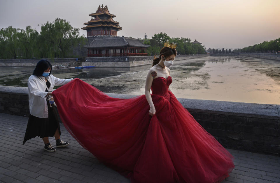 Image: A Chinese woman wears a protective mask as she is helped by a photo assistant while taking pictures in advance of her wedding outside the Forbidden City, (Kevin Frayer / Getty Images file)