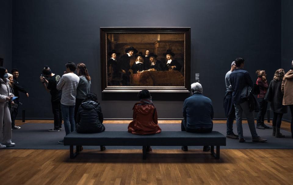 Gente observa el cuadro <em>Los síndicos de los pañeros</em> del pintor neerlandés Rembrandt en el Rijksmuseum de Ámsterdam. <a href="https://unsplash.com/es/fotos/upMGQthYQxY" rel="nofollow noopener" target="_blank" data-ylk="slk:Redcharlie / Unsplash;elm:context_link;itc:0;sec:content-canvas" class="link ">Redcharlie / Unsplash</a>