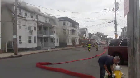 Firefighters work near a building emitting smoke after explosions in Lawrence, Massachusetts, United States in this September 13, 2018 still image from social media video footage by Boston Sparks. Boston Sparks/Social Media/via REUTERS