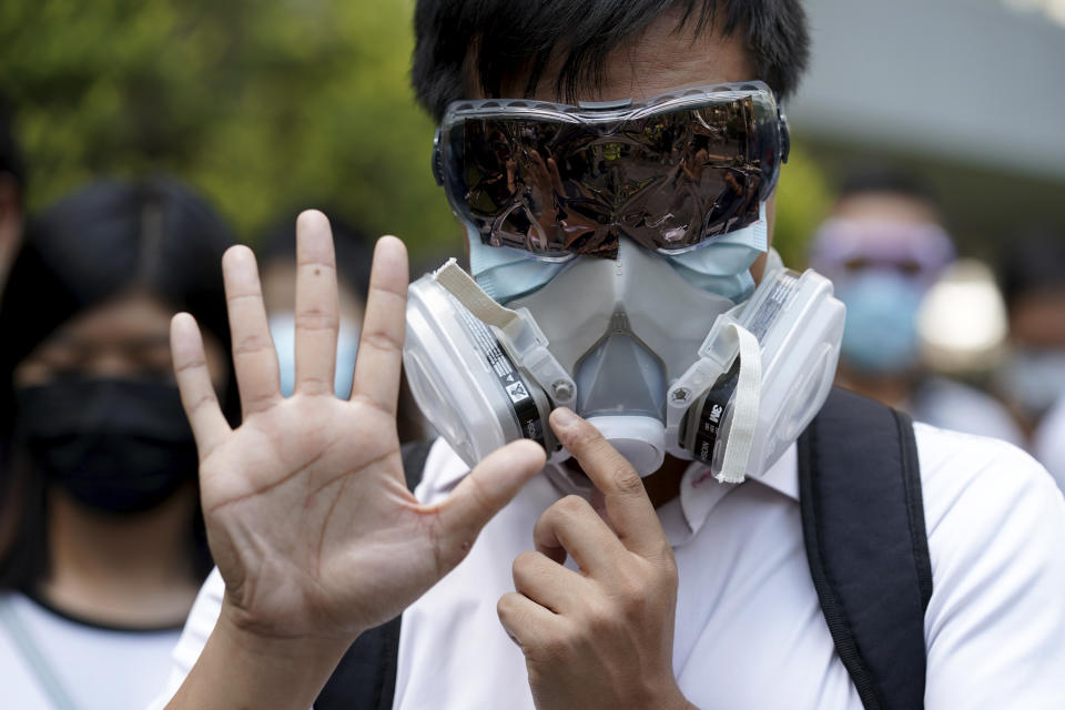 A protester wears a gas mask and holds up his hand to represent the protester's five demands in Hong Kong Friday, Oct. 4, 2019. Hong Kong pro-democracy protesters marched in the city center ahead of reported plans by the city’s embattled leader to deploy emergency powers to ban people from wearing masks in a bid to quash four months of anti-government demonstrations. (AP Photo/Vincent Thian)