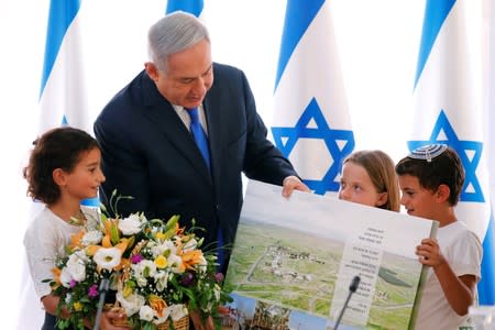 Israeli Prime Minister Benjamin Netanyahu looks at a placard, part of a gift presented to him from Israeli residents of the area, at the start of a weekly cabinet meeting in the Jordan Valley, in the Israeli-occupied West Bank